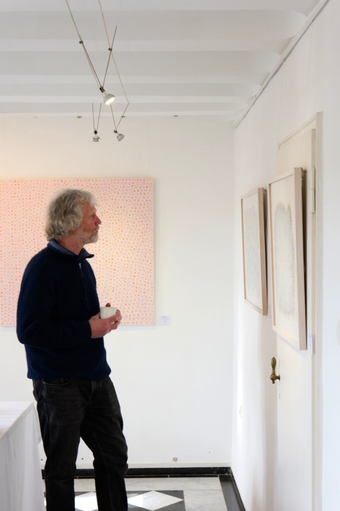 A visitor looking at paintings on the gallery wall.