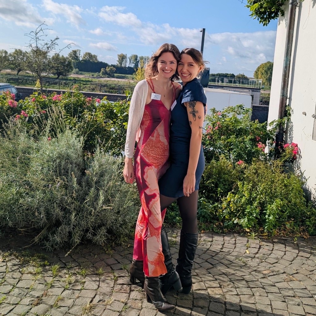 Two people in the garden beside the Rhine, with roses and cobblestones.