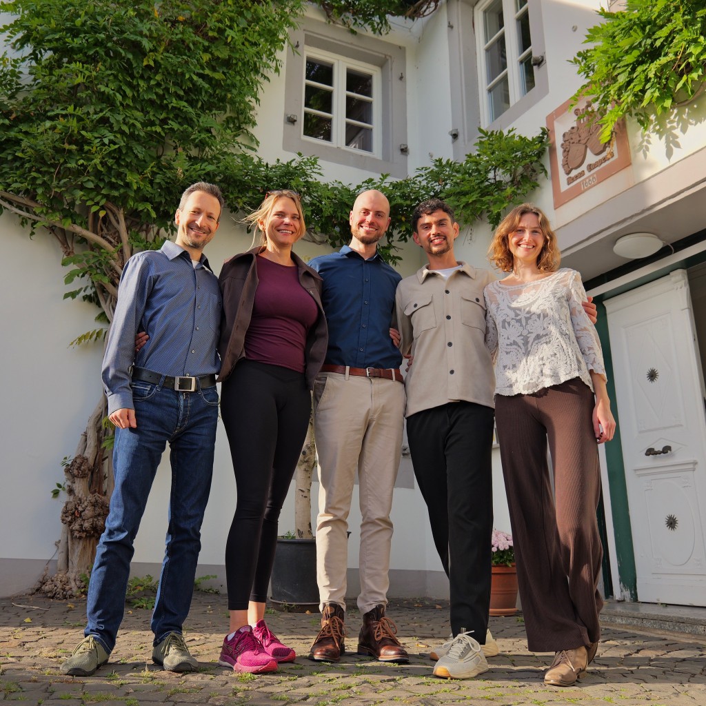 Five people standing together in front of the house.