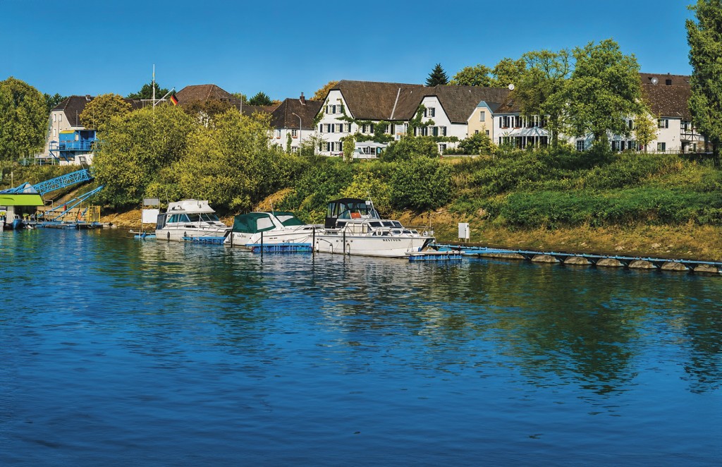 Boats on the Rhine, with houses and trees beyond.
