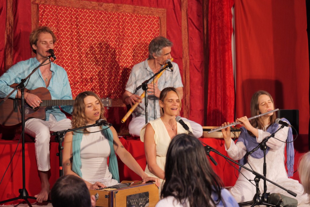 Musicians on a stage with a guitar and flutes.
