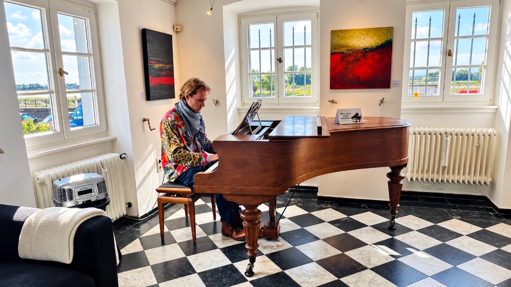 A musician at the wooden grand piano in the hall, the Rhine visible through the windows.