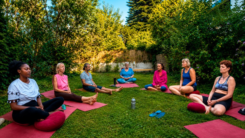 Sitzen im Garten. Ein Meditationskreis auf der Wiese des Yoga Hotels in NRW, bei Köln und Düsseldorf.