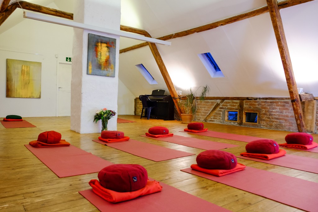 Der Raum, bereit für Yoga und Meditation. Matten, Kissen und ein Klavier im Yoga-Raum in Leverkusen-Hitdorf.